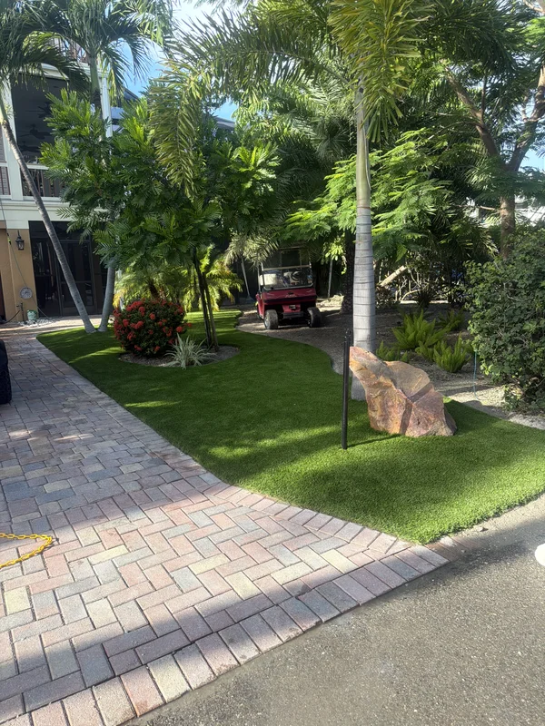 Artificial grass lawn with boulder along a herringbone paver driveway on Captiva Island