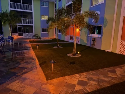 Condo courtyard with artificial turf, paver walkway, path lights and uplit palms at night