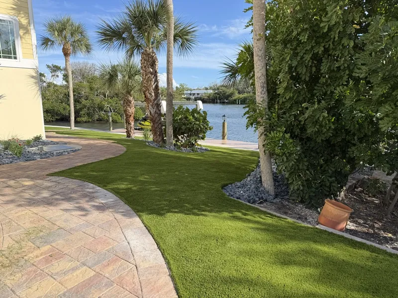 Curved artificial grass lawn with paver walkway on the water in Englewood