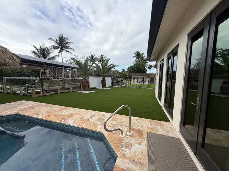 Travertine pool deck and artificial grass canal backyard in Fort Myers