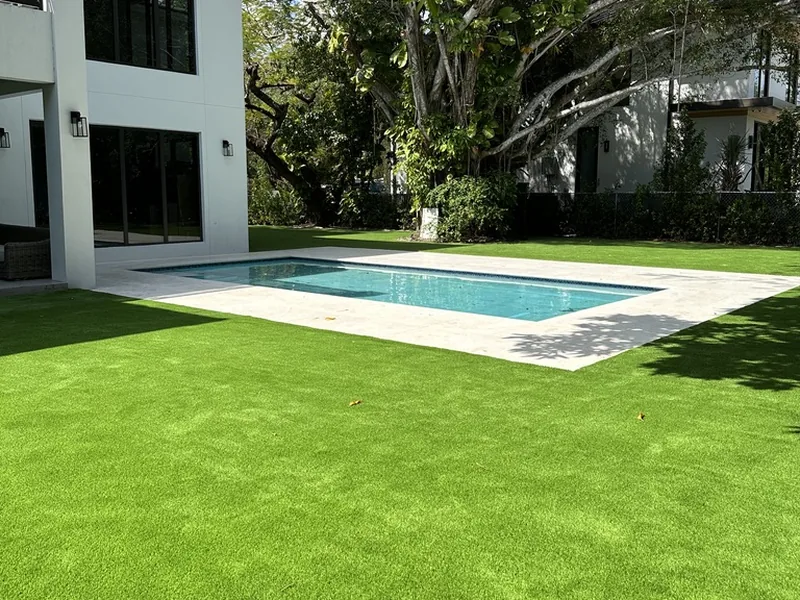 Artificial grass lawn around a pool under a large shade tree