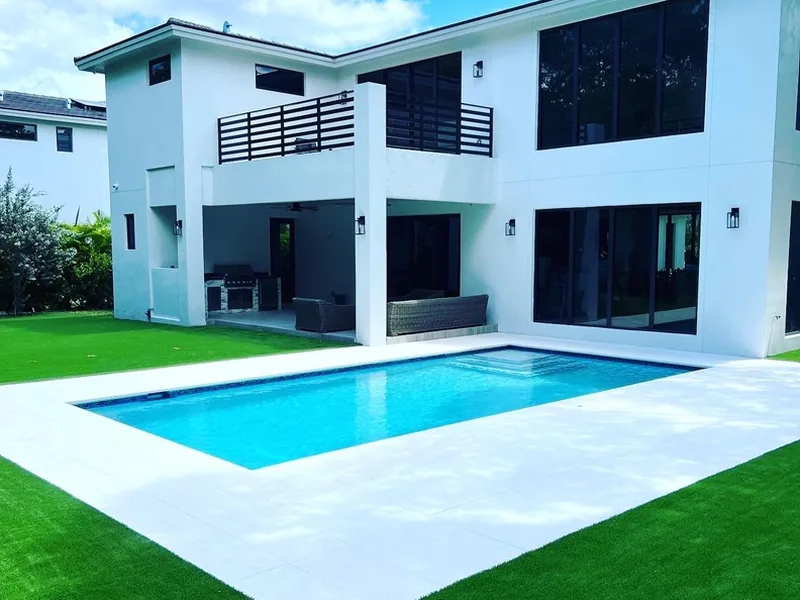 Modern two-story home with pool deck and artificial grass lawn