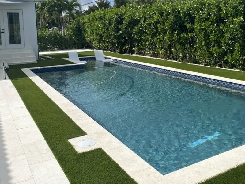 Rectangular pool with travertine coping, turf border and privacy hedge