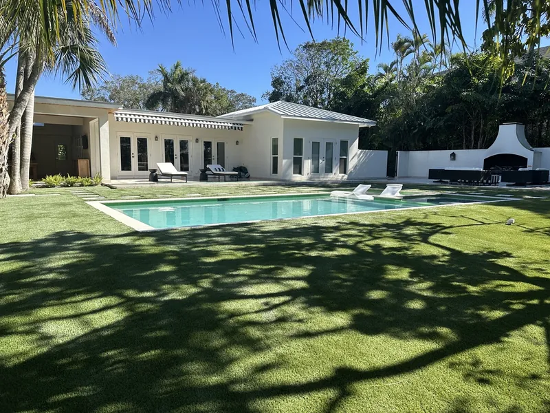Luxury Naples pool house with artificial grass lawn and palm shadows