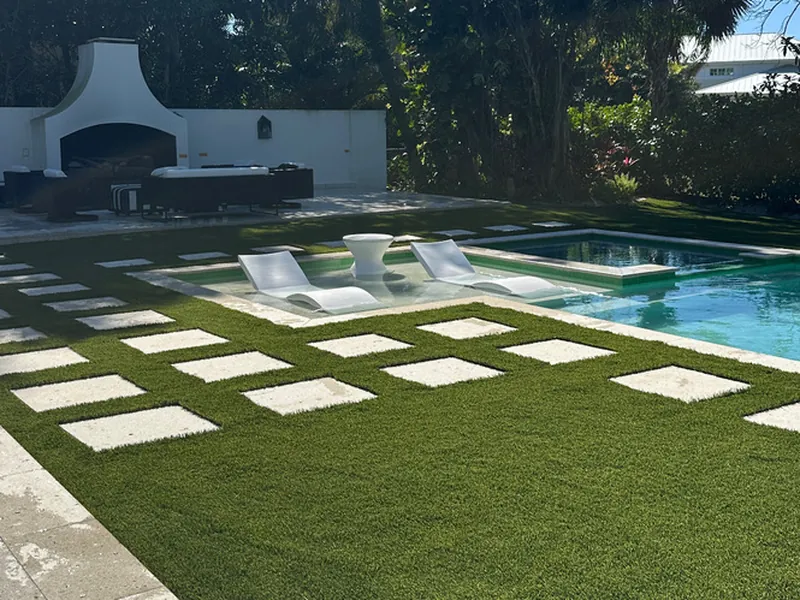 Artificial turf and stepping pads leading to an outdoor fireplace in Naples