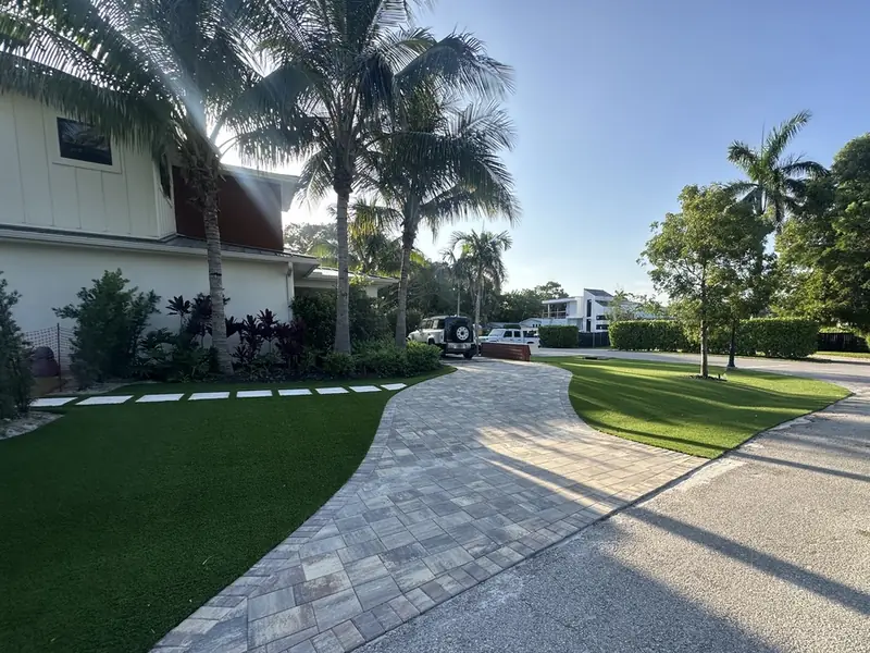 Curved paver driveway framed by turf in Naples, FL by Creative Grounds