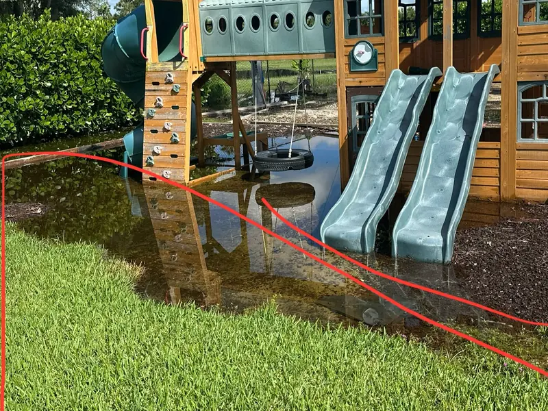 Before: flooded mulch and grass under a backyard playset in Naples FL
