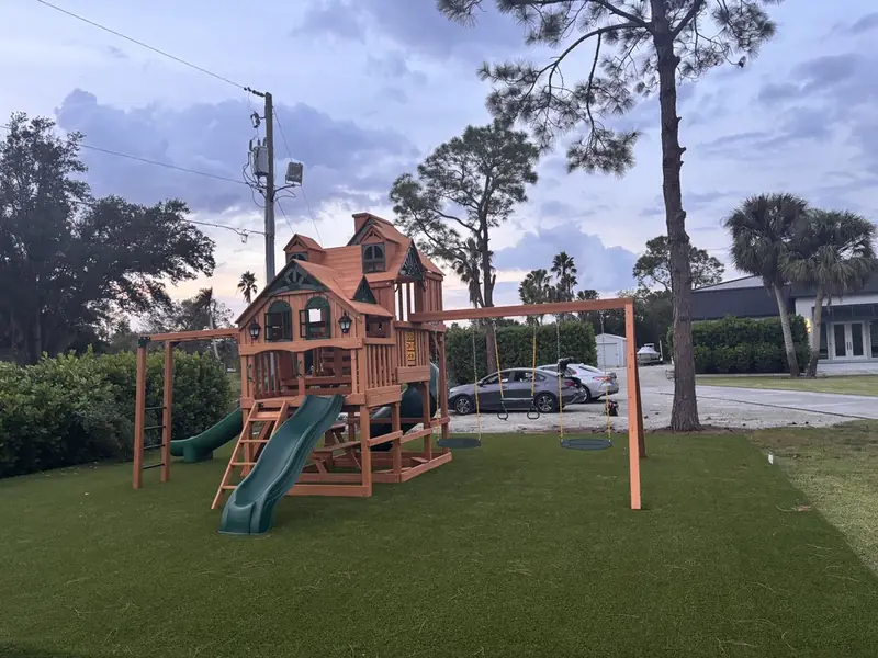 Swing set and playset on turf by Creative Grounds in Naples