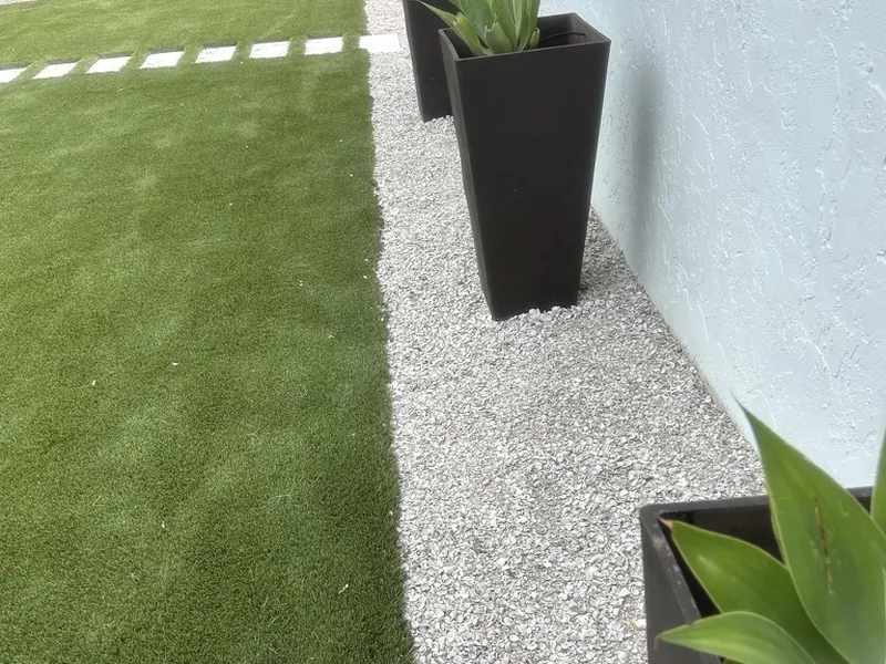 Clean artificial turf edge against shell rock and planters in Naples