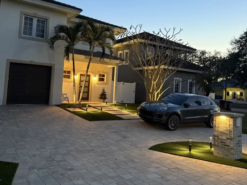 Paver driveway and front facade with landscape lighting at dusk