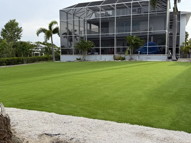 Large artificial grass backyard behind a pool cage in Port Charlotte