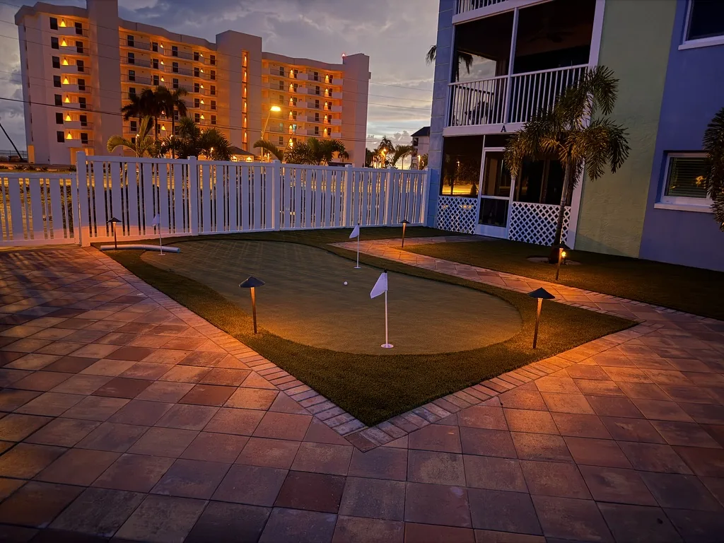 Putting green with path lights, artificial turf and paver patio at dusk