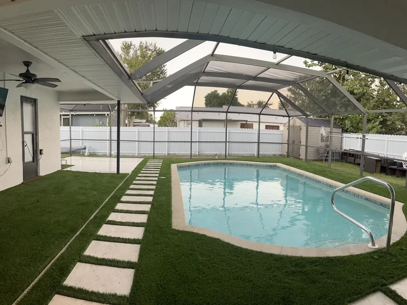 Screened lanai pool surrounded by artificial turf and stepping pads