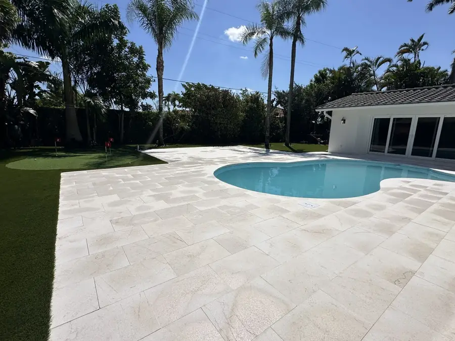 Travertine pool deck with putting green by Creative Grounds