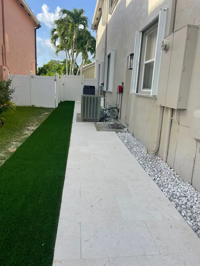 Travertine side-yard walkway with turf by Creative Grounds