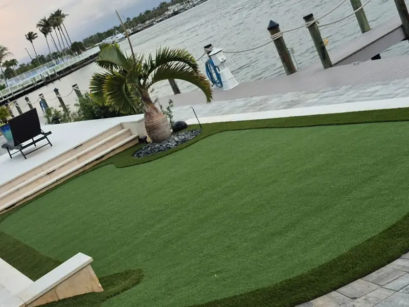 Waterfront putting green framed by pavers and a seawall